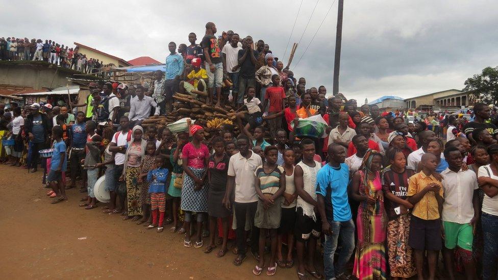 Mourners look on as victims of a mudslide are buried at the cemetery of Freetown on August 17, 2017.