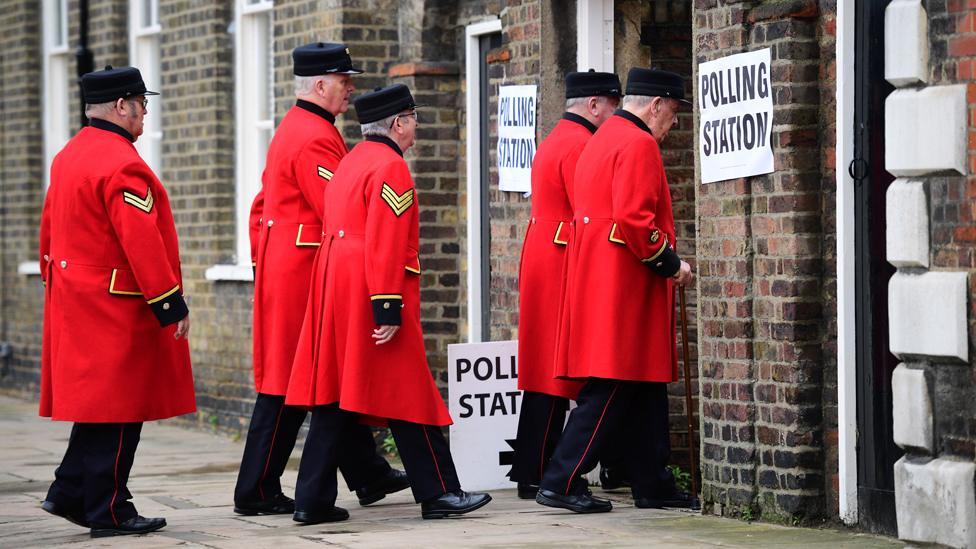 Chelsea pensioners in red uniforms enter a polling station together