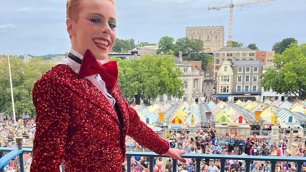 Korben wears a red dress/tuxedo combination for Norwich Pride 2022