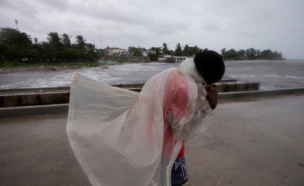 A boy covers himself with a raincoat as he walks along a pier ahead of Hurricane Matthew in Les Cayes, Haiti, on October 3, 2016.