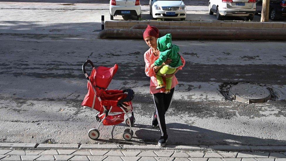 File photo taken in 2019 shows a woman walking in an ethnic Uighur neighbourhood in Aksu in China's northwest Xinjiang region