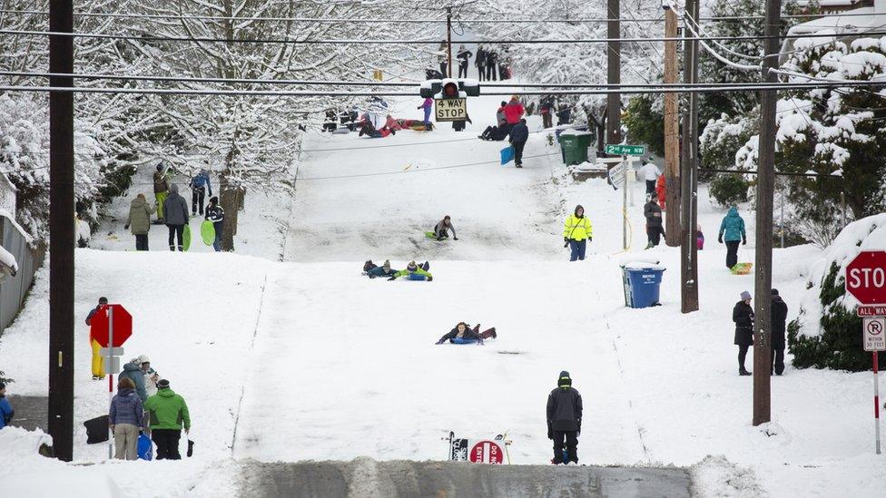 People sledge down a road