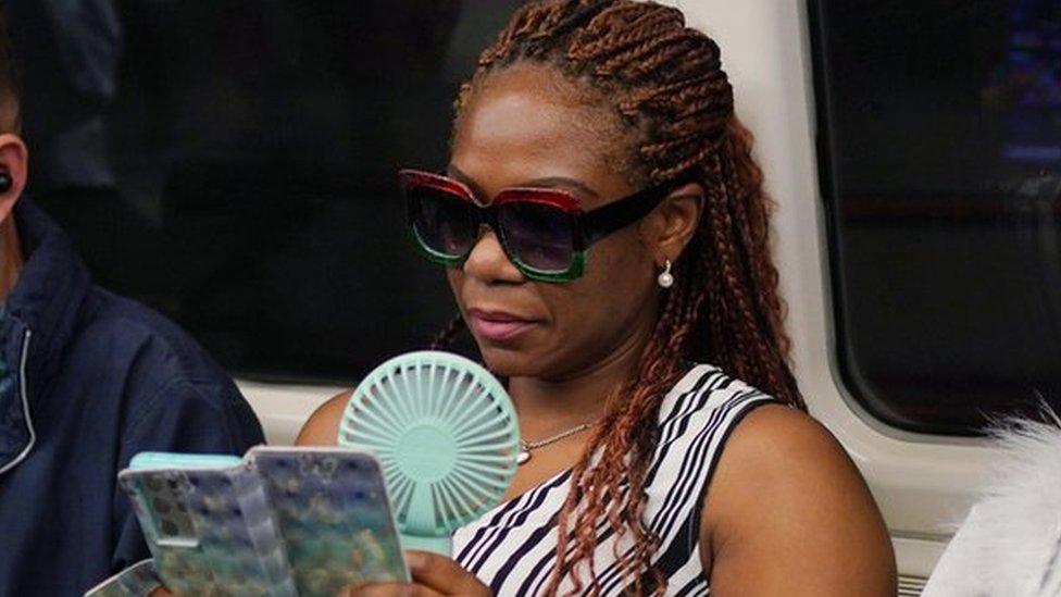 A commuter with a portable handheld fan on a Jubilee line train