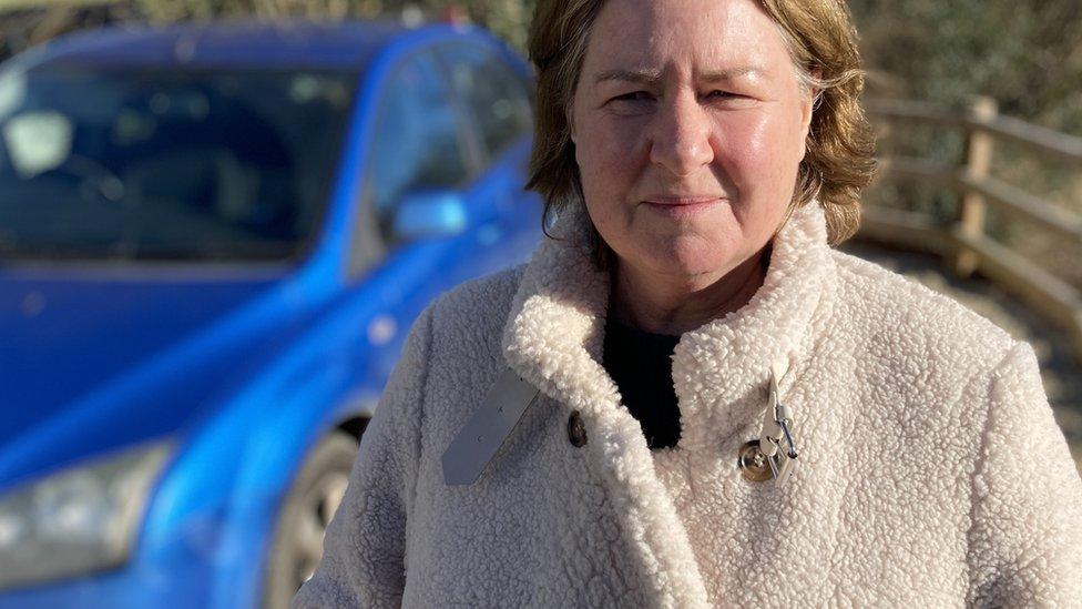 Caroline Nesbitt standing by a car looking at the camera