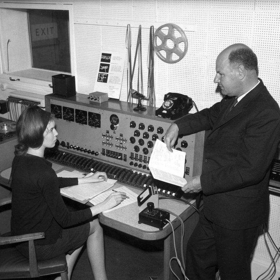 Delia Derbyshire seated at mixing desk with Desmond Briscoe