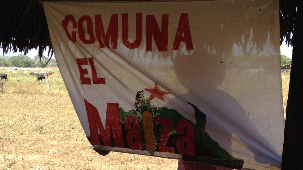 A man holds up a banner reading "Comuna el Maizal" in February 2016