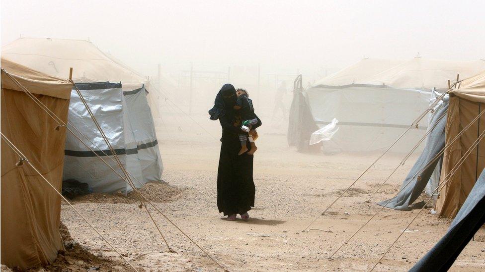 An Iraqi woman walks through a dust storm at a refugee camp outside Falluja