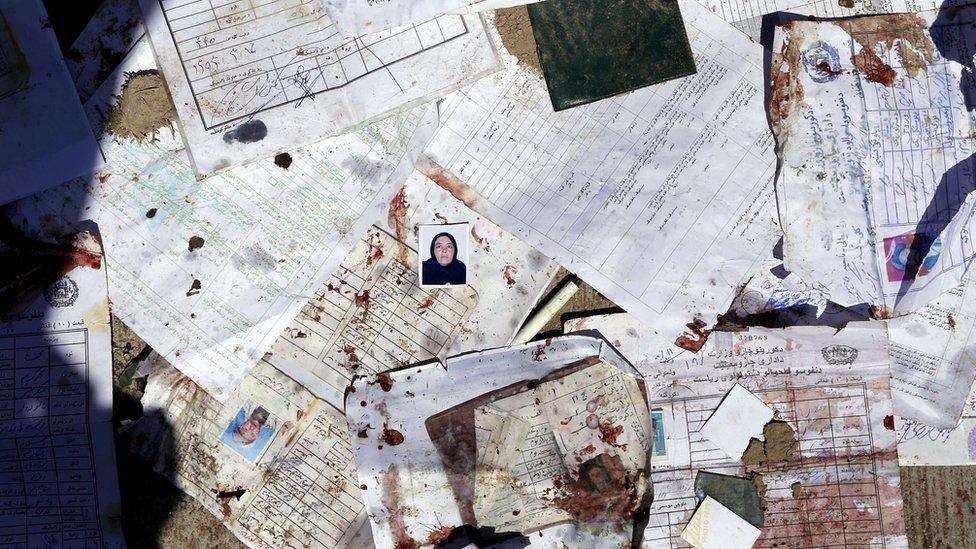 Passport photos and forms lie in the street after the bomb attack in Kabul, 22 April