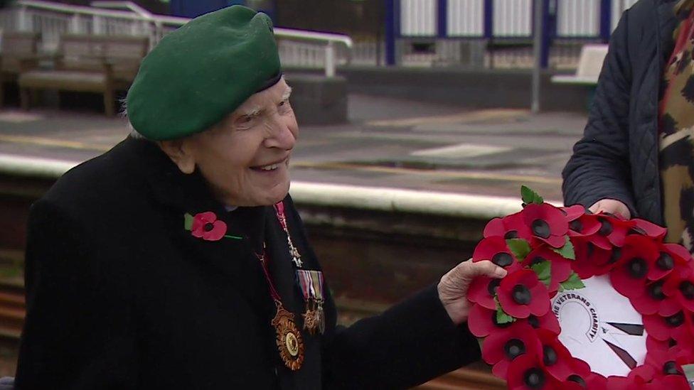 Harry Billinge smiles while holding wreath