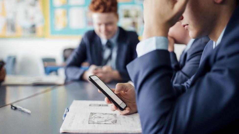 Pupils using their mobile phones in a classroom