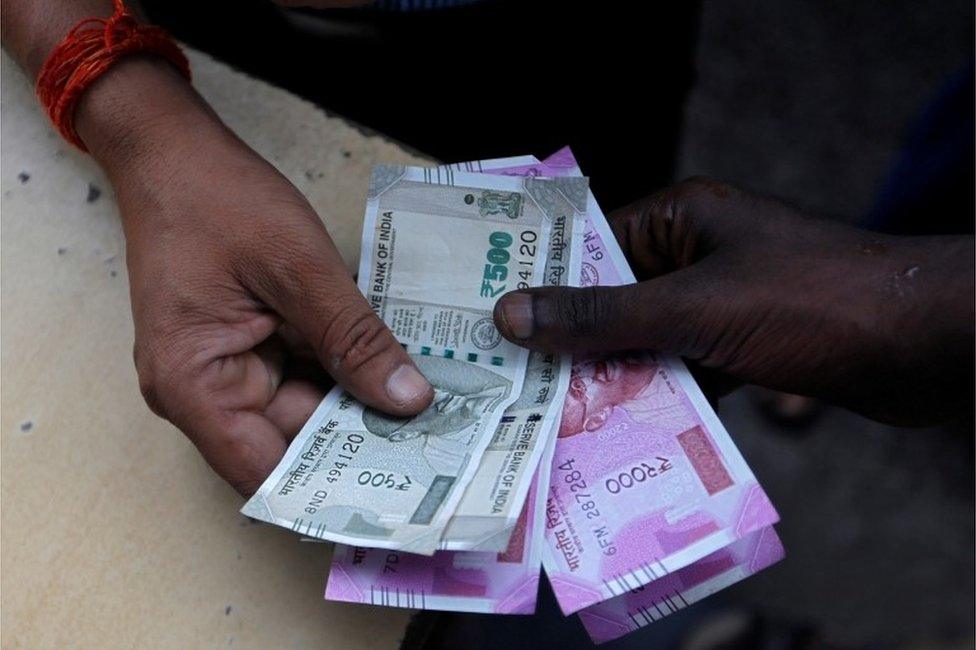 A customer hands Indian currency notes to an attendant at a fuel station in Mumbai, India, August 13, 2018. REUTERS/Francis Mascarenhas