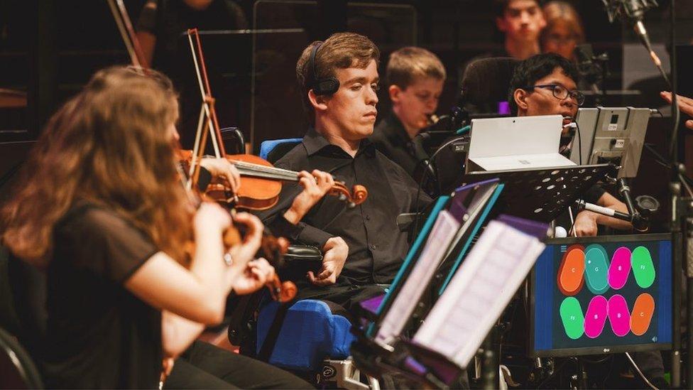 Alessandro Vazzana playing the Clarion in an orchestra, with a violinist next to him