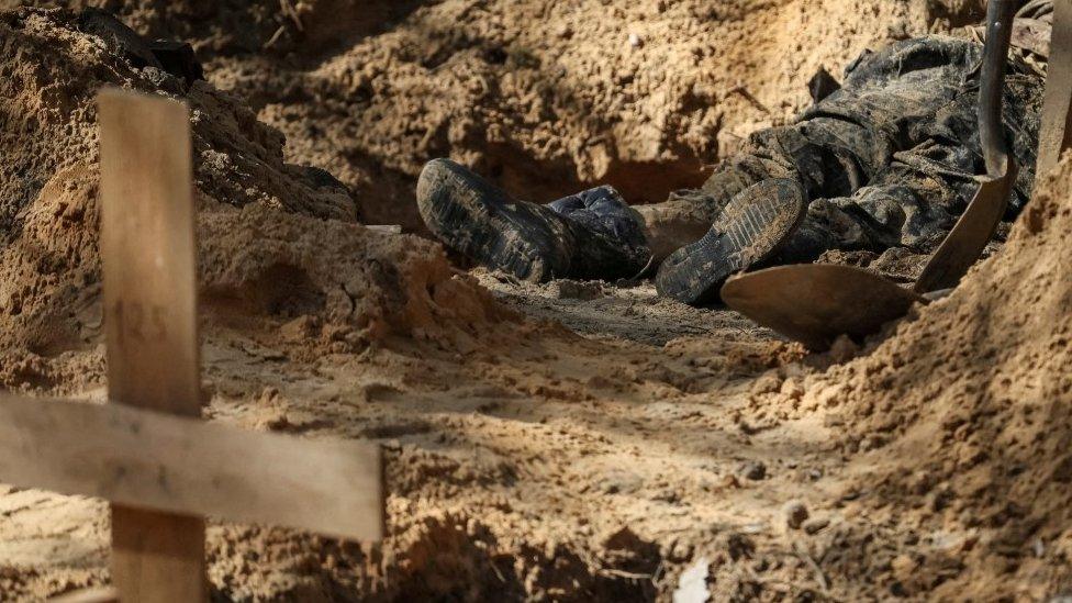 An exhumed body lies at a grave site in the town of Izyum, 17 September 2022