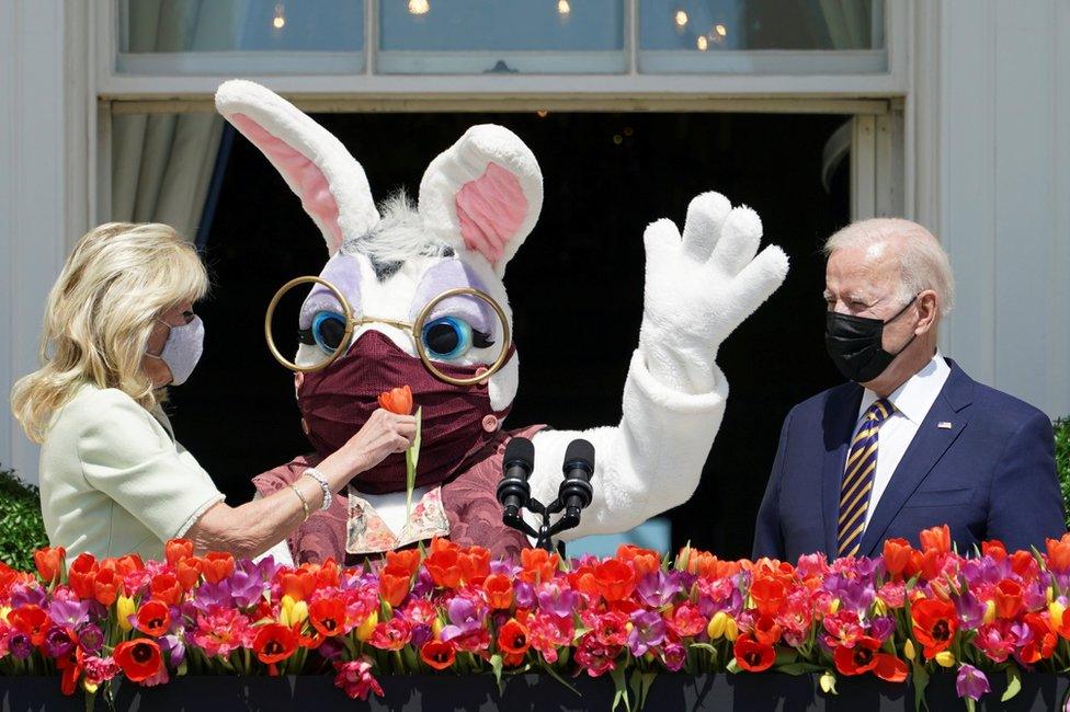 US President Joe Biden waits to deliver his remarks on the tradition of Easter, next to first lady Jill Biden and a person wearing an Easter Bunny costume at the Blue Room Balcony of the White House in Washington, 5 April 2021.