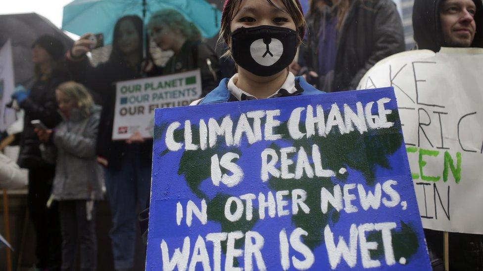 Demonstrators holds signs during the People's Climate March outside Trump International Hotel & Tower on April 29, 2017 in Chicago, Illinois.