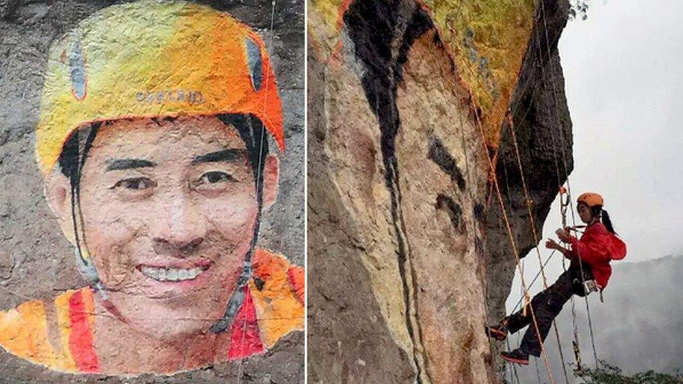 Woman painting mural on side of cliff