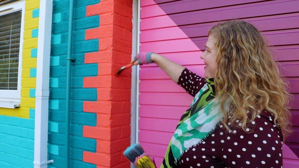 Artist Tash Frootko painting a building