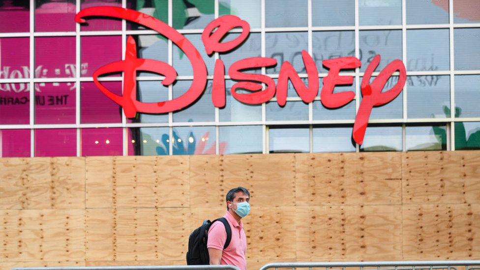 A man in a mask walks past the Disney store in Times Square, New York