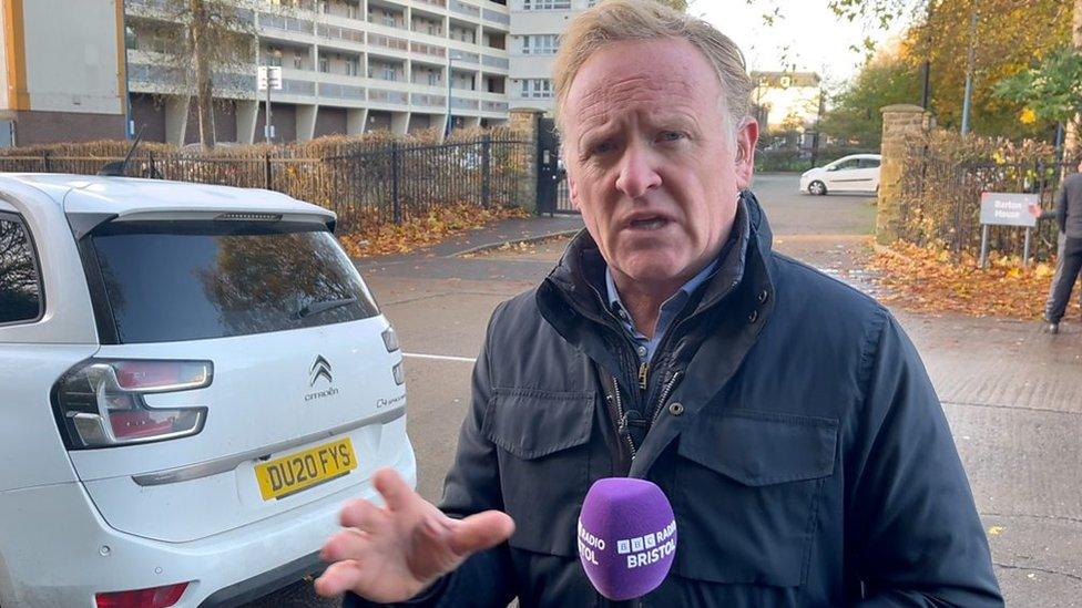 Reporter stands in front of the flats