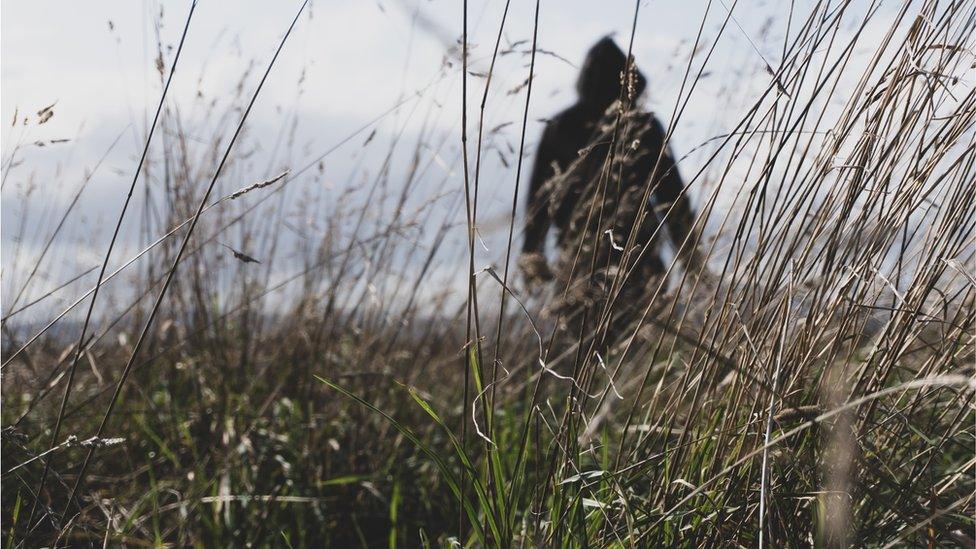 Hooded man in long grass