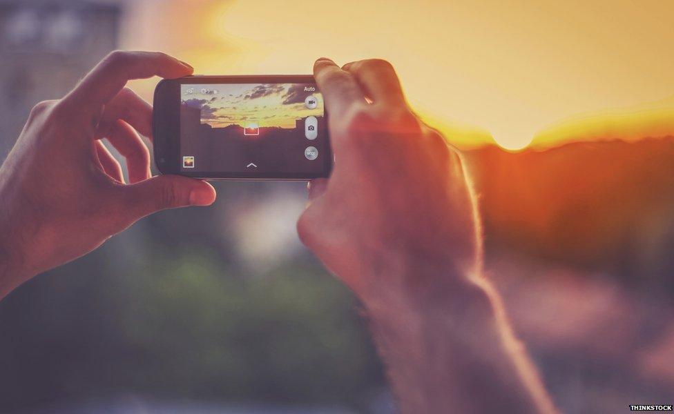 Man taking photo of sunset on his phone