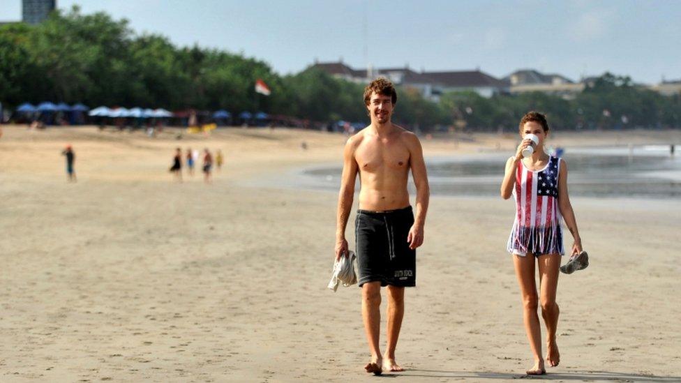 Foreign tourists are pictured walking along a beach