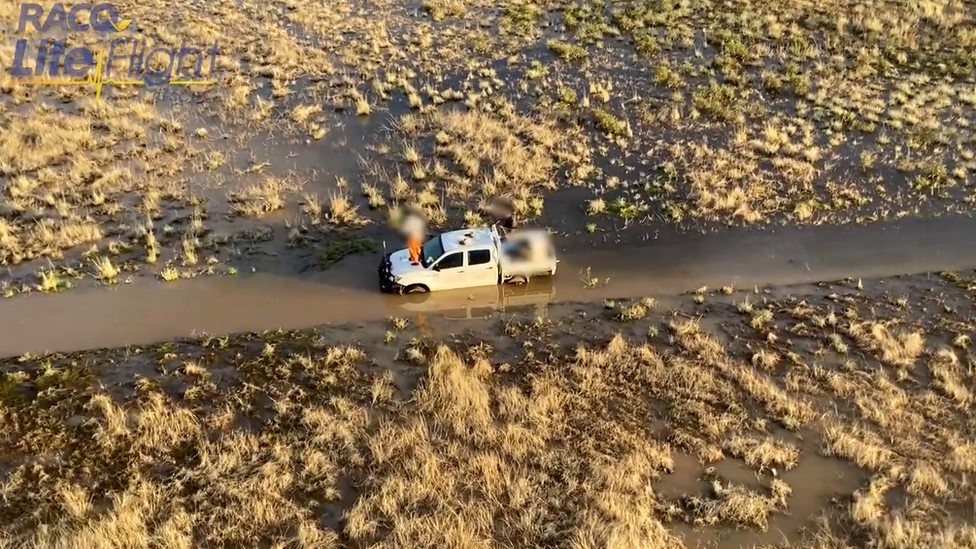 Aerial shot of the father and son sitting on top of their stranded vehicle