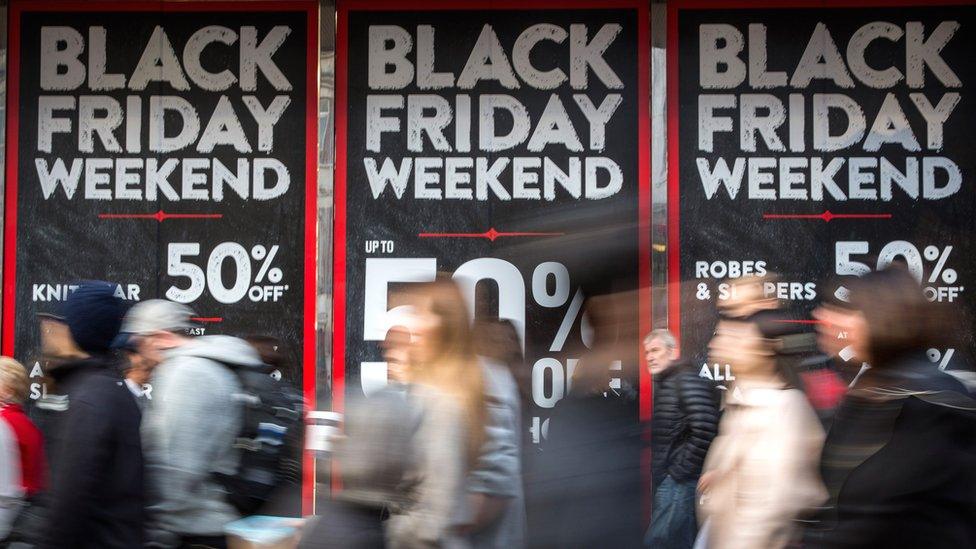 People walk past a shopfront on Oxford Street advertising 'Black Friday' discounts.