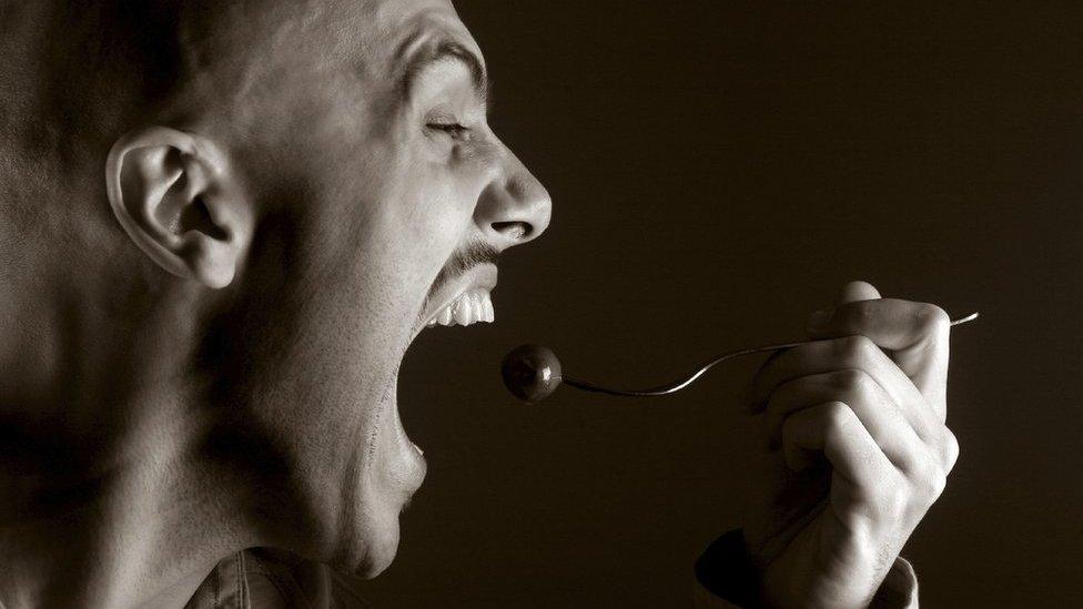 Man eats food on fork hungrily