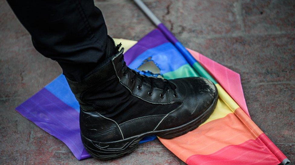 A Turkish anti-riot police officer steps on a rainbow flag during a rally staged by the LGBT community in Istanbul (19 June 2016)