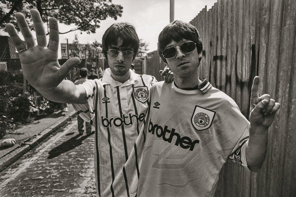 Liam and Noel Gallagher wearing Manchester City football shirts