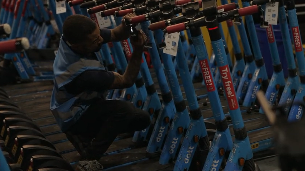 Man fixing e-scooters at Dott depot