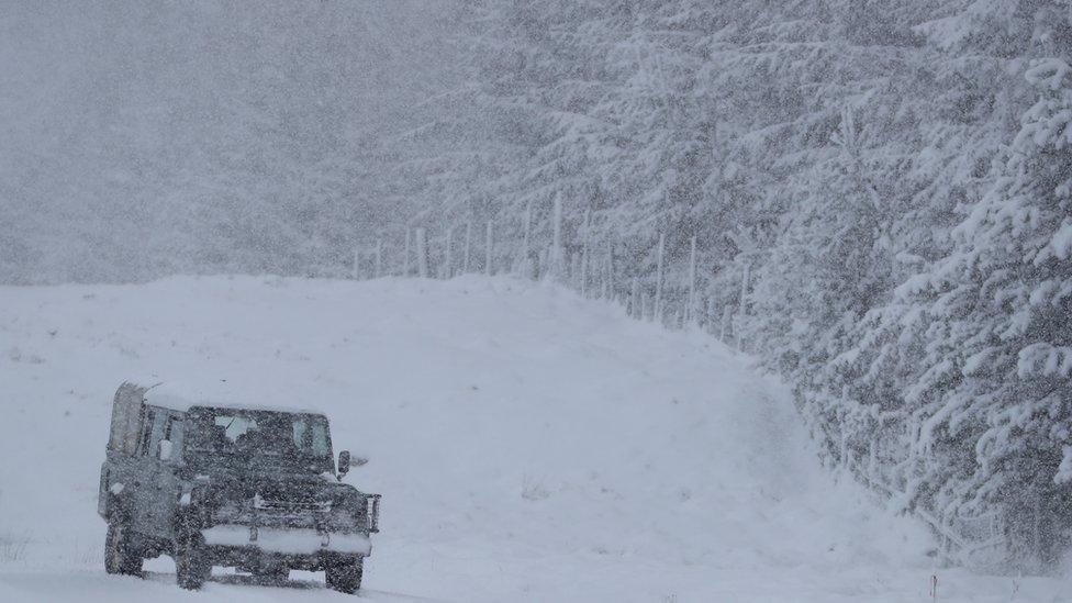 A Land Rover drives on a snow-covered road near Trinafour, Scotland.