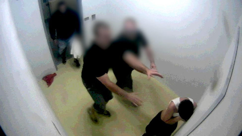 A youth detainee being forcibly stripped by prison guards