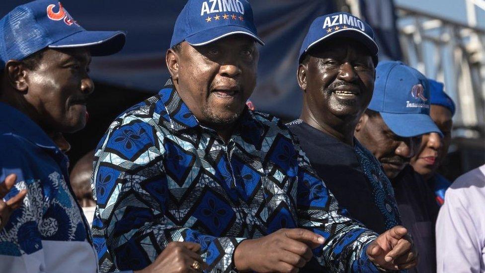 Kenya's President, Uhuru Kenyatta (C) dances to a popular campaign jingle as he stands on a podium next to his former political nemesis, Raila Odinga (R) - 2022