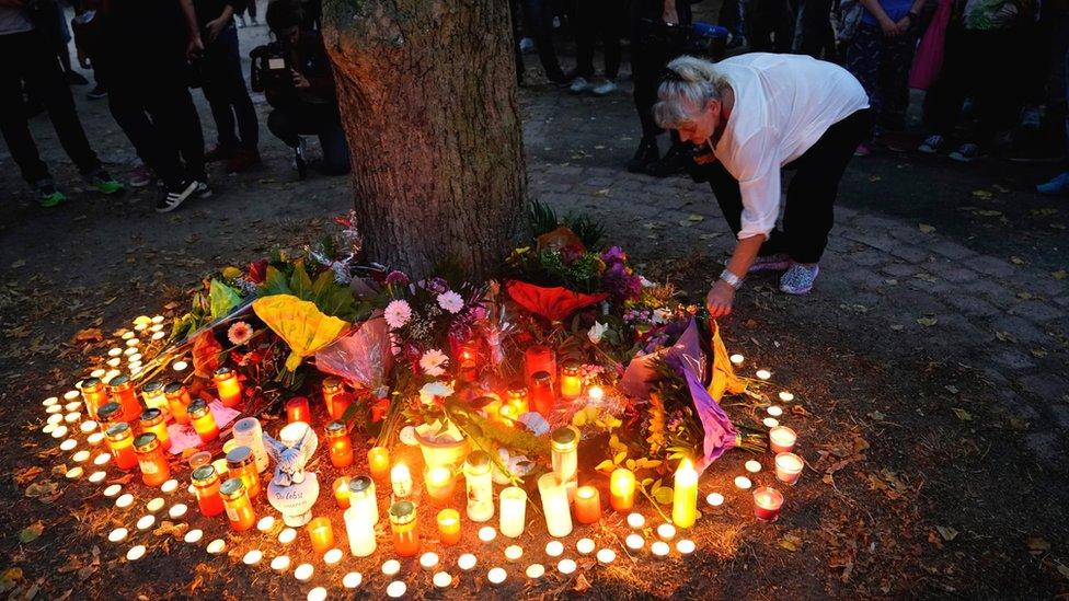 A woman lights a candle after a mourning march for a 22-year-old man killed in Köthen, Germany, 9 September 2018