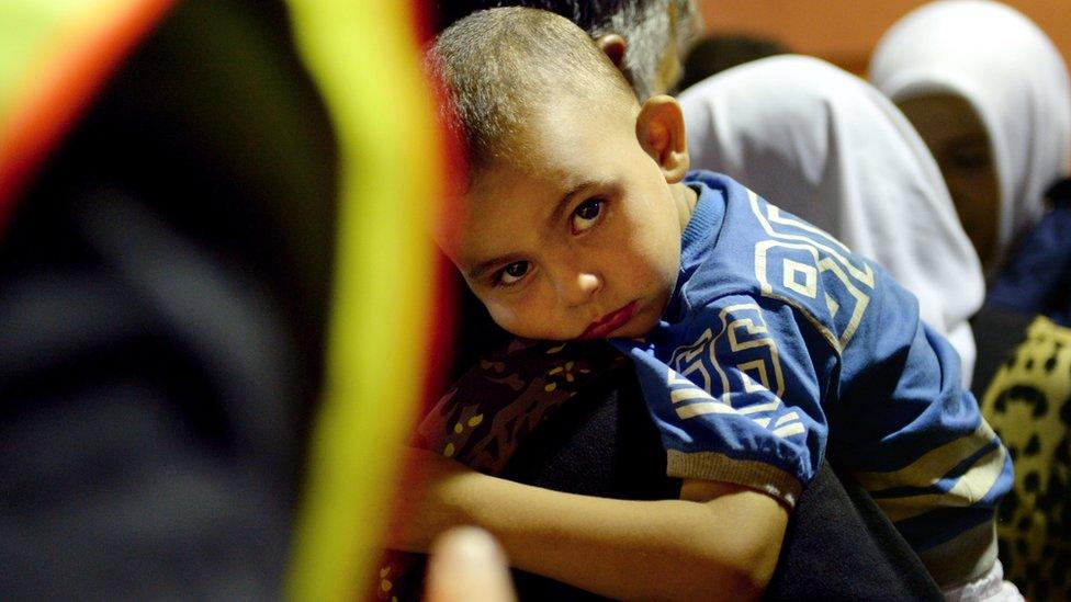 A man holds a young boy at the main train station in Munich, southern Germany, after migrants arrived from Hungary on 31 August 2015.