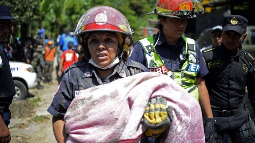 Rescuers carry a children victim of a landslide at Cambray village, in Santa Catarina Pinula municipality, Guatemala on October 2, 2015.