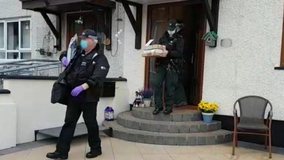 Members of the Paramilitary Crime Task Force leaving a house, carrying parcels