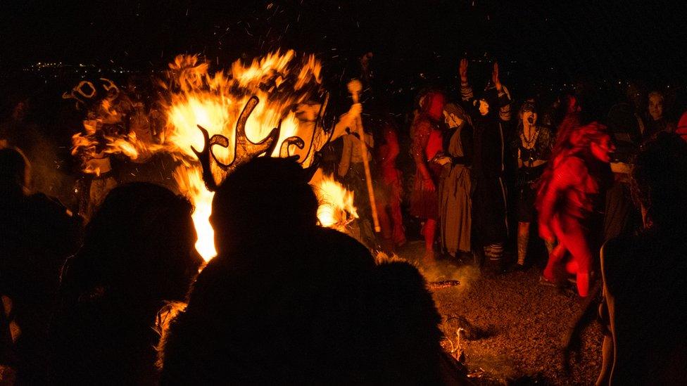 Participants and onlookers gather around a fire