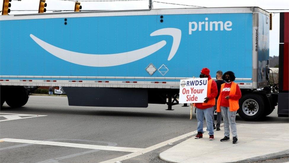 People hold a union placard at the Amazon facility in Bessemer, AL