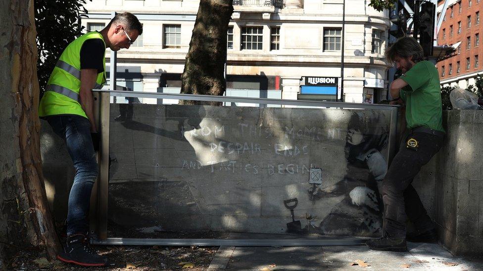 Glass casing being installed around Banksy mural