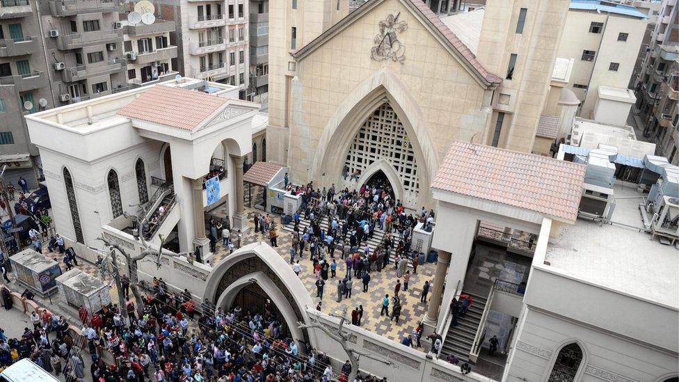 People gather in front of Mar Girgis church after a bomb explosion