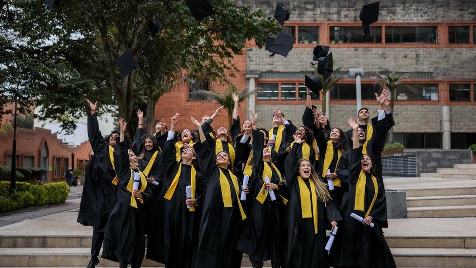 Group of graduates throwing their mortarboards in the air