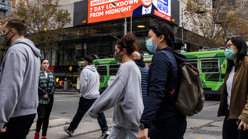 Young people wearing masks walk down a Melbourne street early May 2021