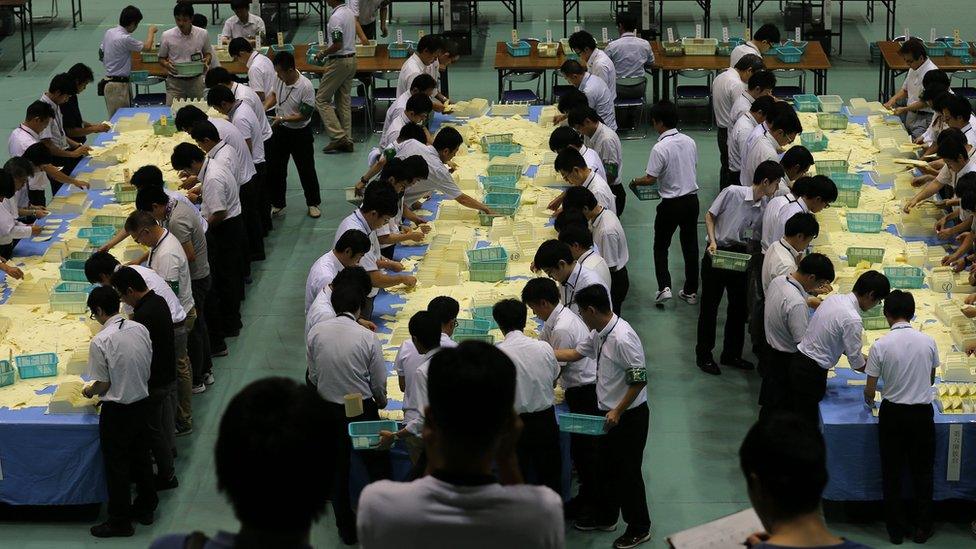 Election staff members count votes, which were cast in the parliament's upper house election, at a ballot counting centre in Himeji, Japan
