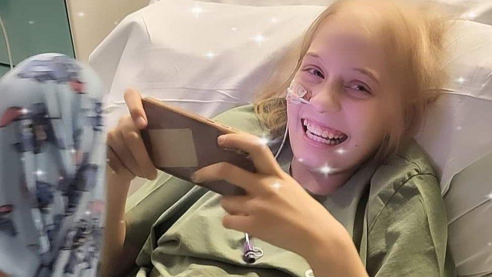 Teenager in hospital bed with her phone