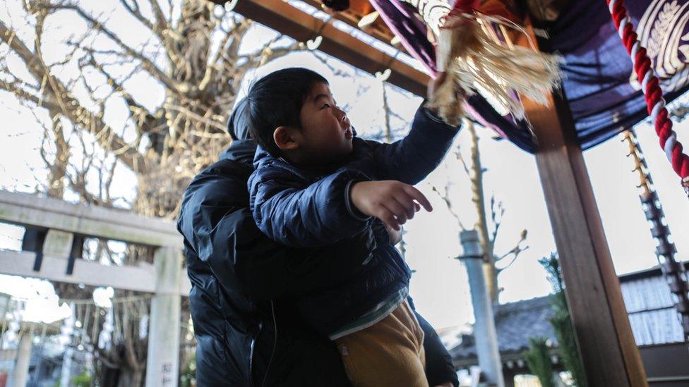 Japanese man helps son to ring a bell