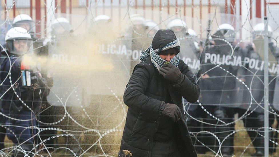 Polish riot police officers and a migrant are seen near the Kuznica crossing point