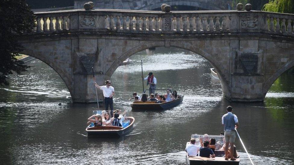 People punt along the river Cam on a hot day in Cambridge